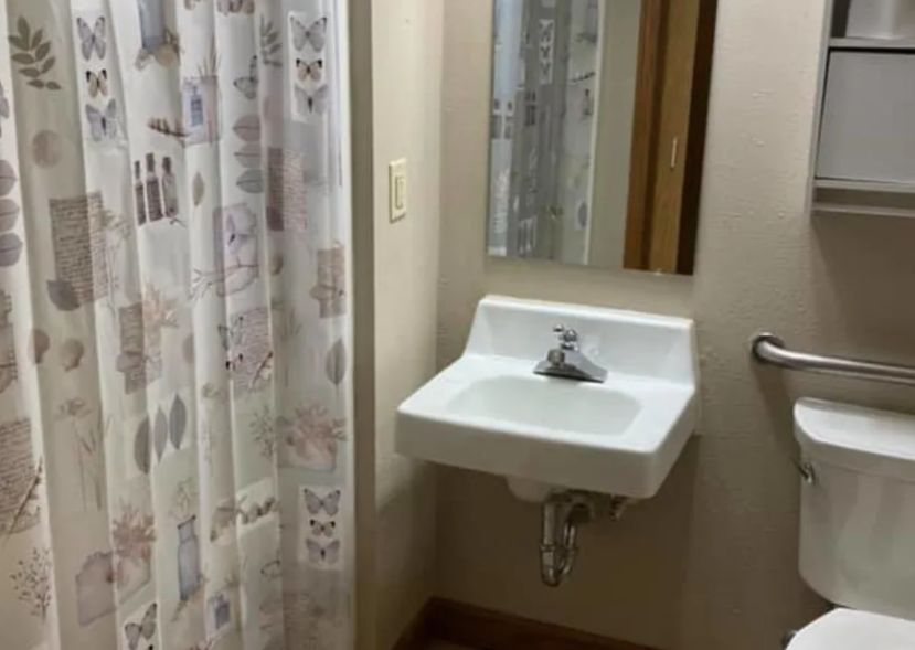 A small bathroom with a wall-mounted sink and a patterned shower curtain.