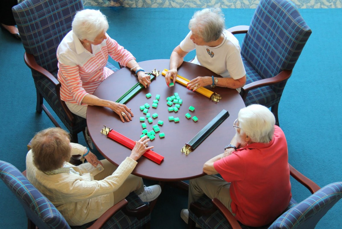 A group of seniors playing a game at a table indoors.