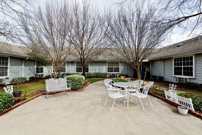 A cozy patio area with outdoor seating surrounded by trees and a garden.
