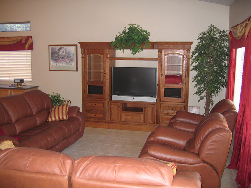 A cozy living room featuring a leather sofa arrangement and a wooden TV stand.