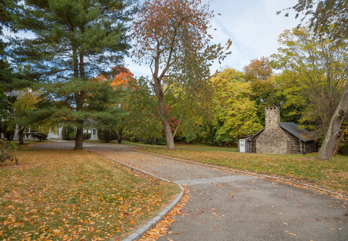 A peaceful autumn scene with a winding pathway surrounded by colorful trees and a small stone building.