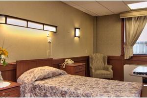 A hospital room with a single bed, nightstand, and chair.