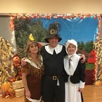 A group of three people dressed in Thanksgiving-themed costumes, surrounded by festive autumn decorations.