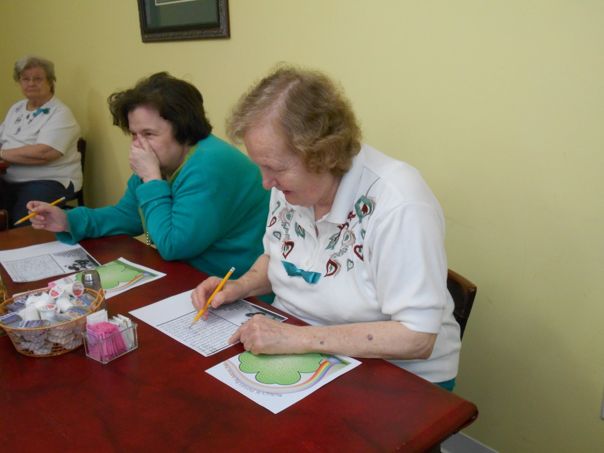 Two women sitting at a table, engaged in writing activities.