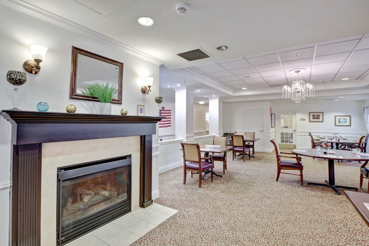 A cozy and elegantly furnished indoor space featuring a fireplace, tables, and chairs.