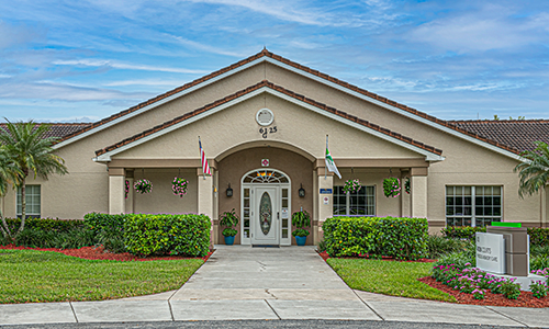 A symmetrical building entrance with flags and manicured landscaping.