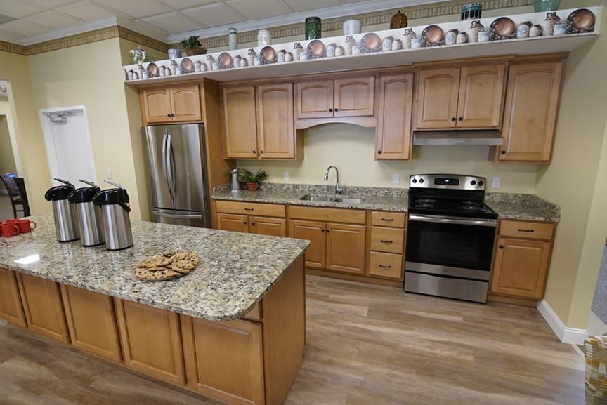 A modern kitchen with wooden cabinets and a granite island, featuring stainless steel appliances.