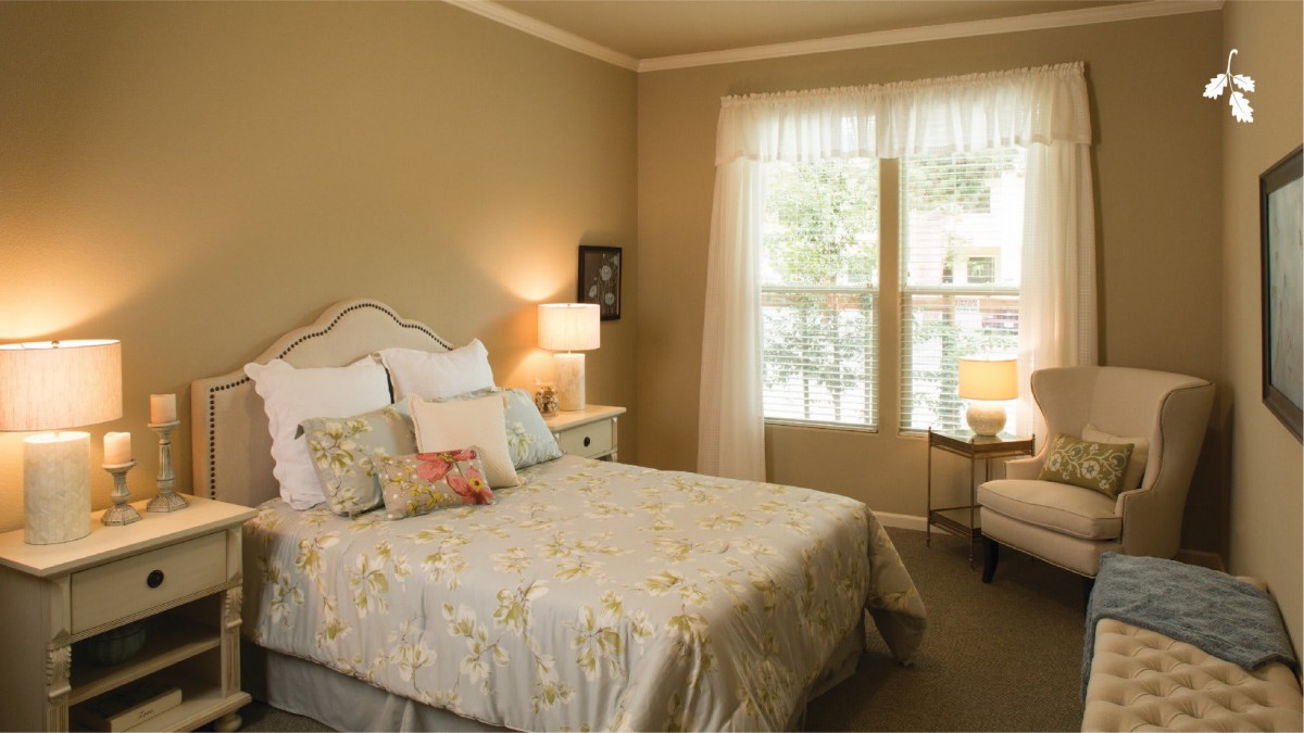 A cozy bedroom with a neatly made bed and a window letting in natural light.