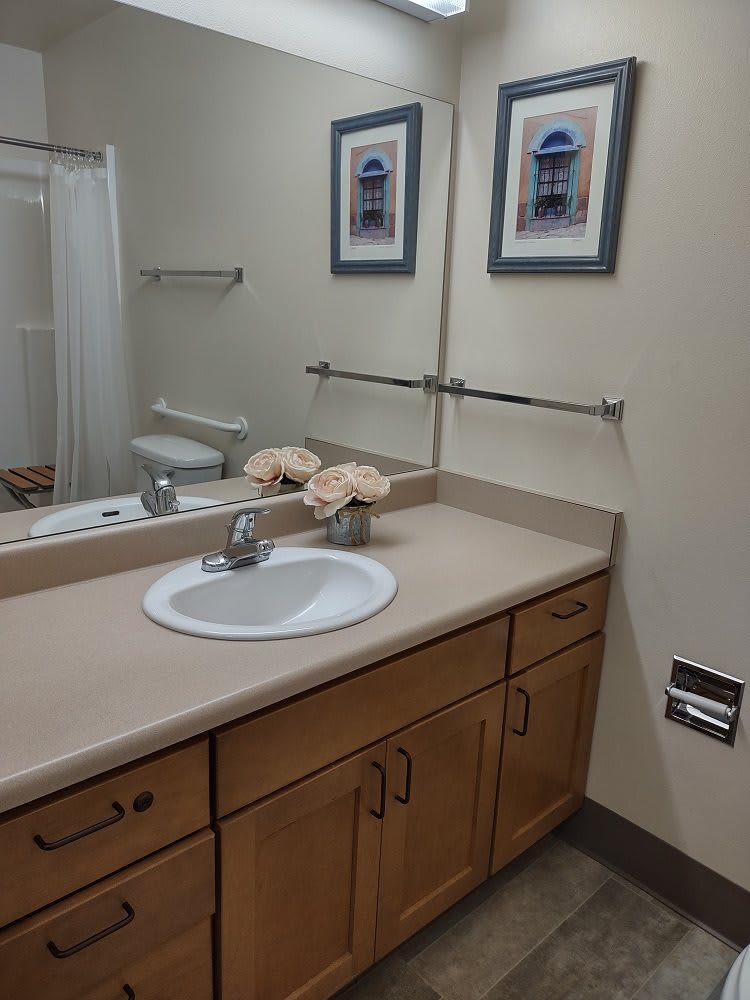 A clean and organized bathroom with a sink, mirror, and decorative elements.