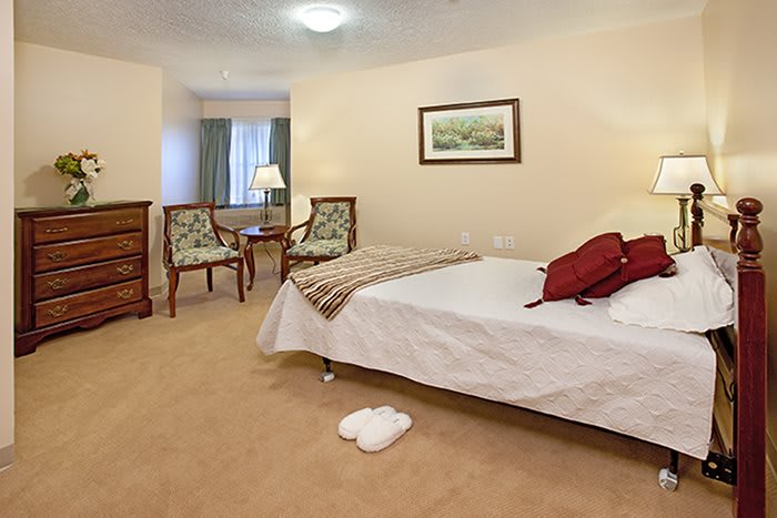 A cozy hotel room with a neatly made bed, chairs, and warm lighting.