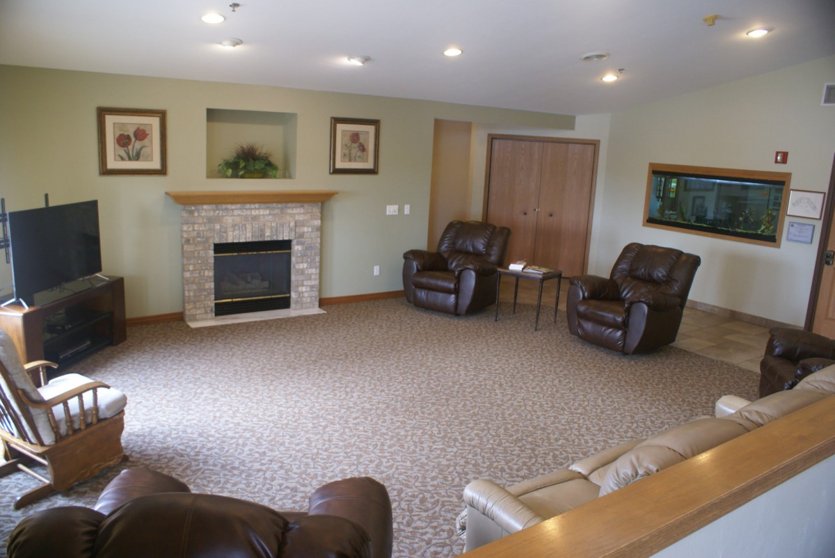 A cozy living room featuring a fireplace, comfortable armchairs, and a carpeted floor.