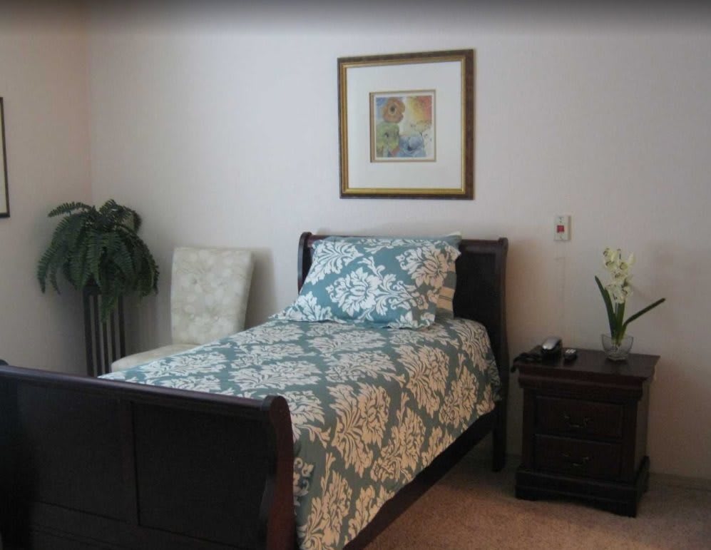 A neatly arranged bedroom with a single bed, a nightstand, and decorative elements.