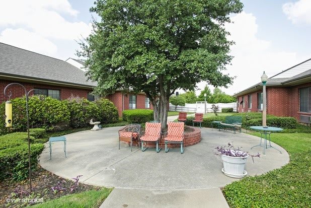 A peaceful courtyard with chairs and a central tree providing shade.