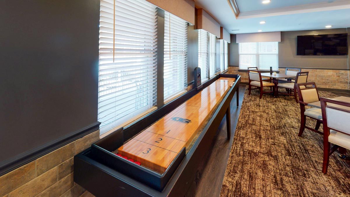 A shuffleboard table in a well-lit game room setting.