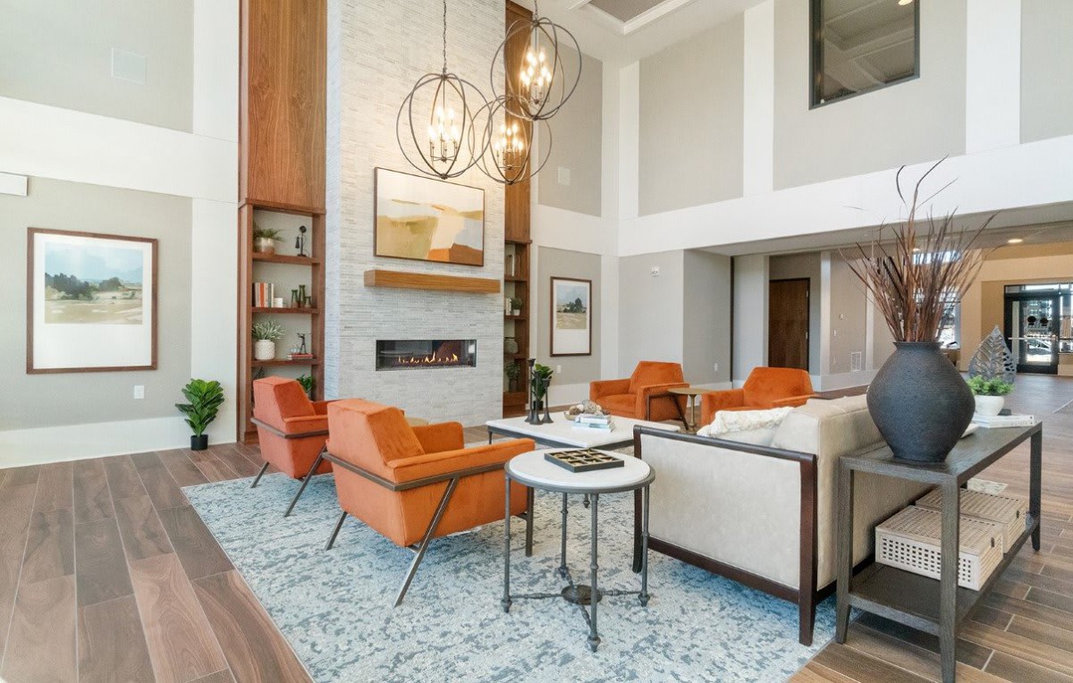A modern living room with orange chairs and elegant chandeliers.