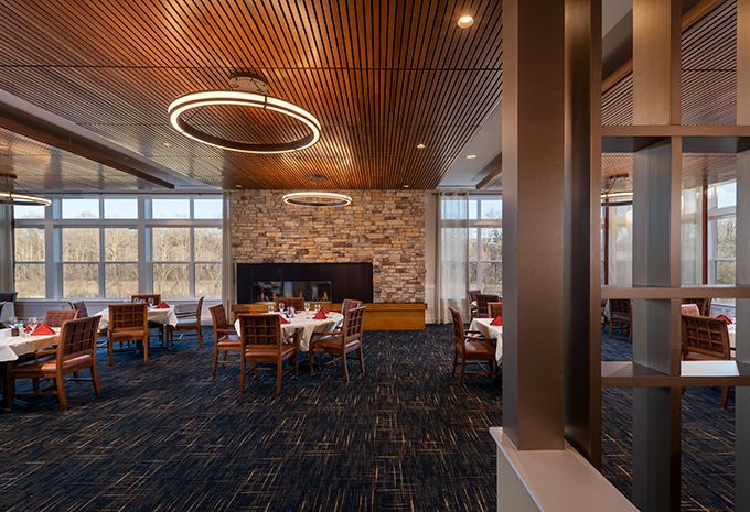 A modern dining area featuring a wooden ceiling, stone accent wall, and elegant lighting fixtures.
