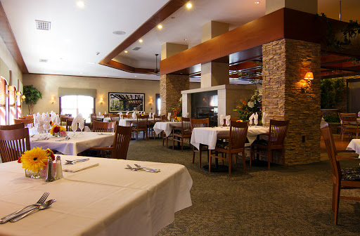 A spacious and elegantly designed restaurant interior featuring well-set tables and a cozy atmosphere.