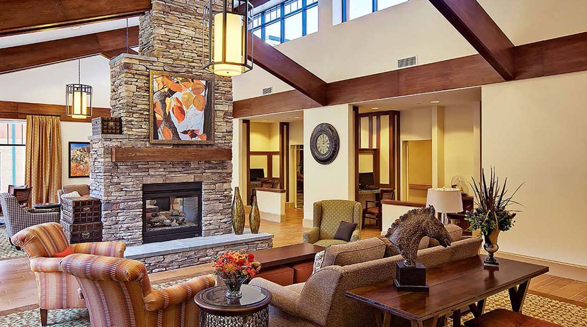 A modern and cozy living room with a stone fireplace, stylish furniture, and unique artwork.