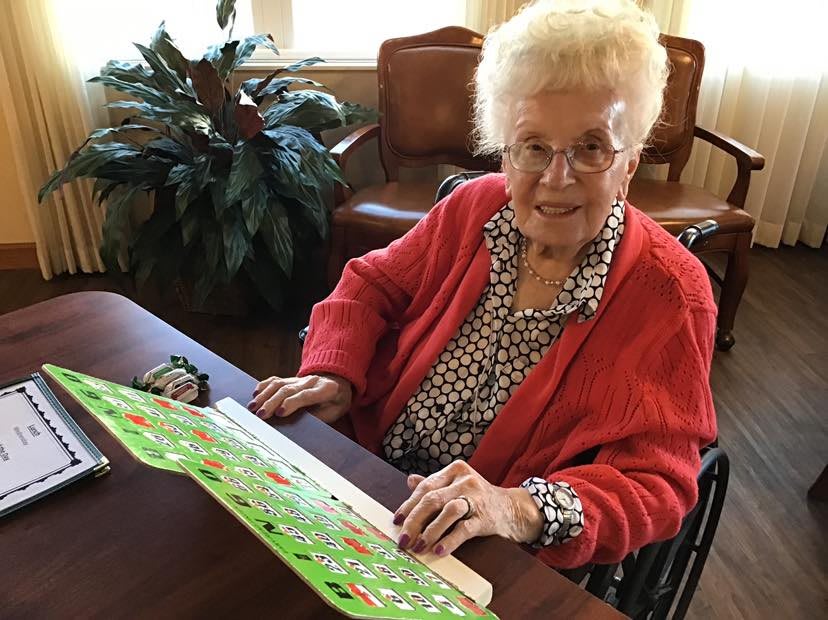 An elderly woman sitting at a table working on a puzzle.