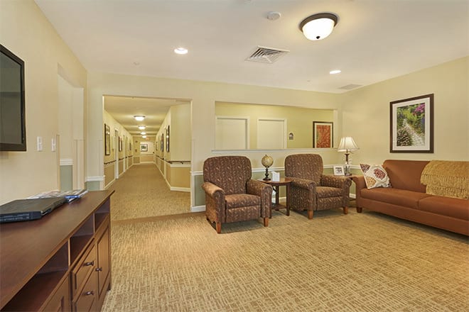 A warmly lit lobby area featuring comfortable seating and a long hallway.