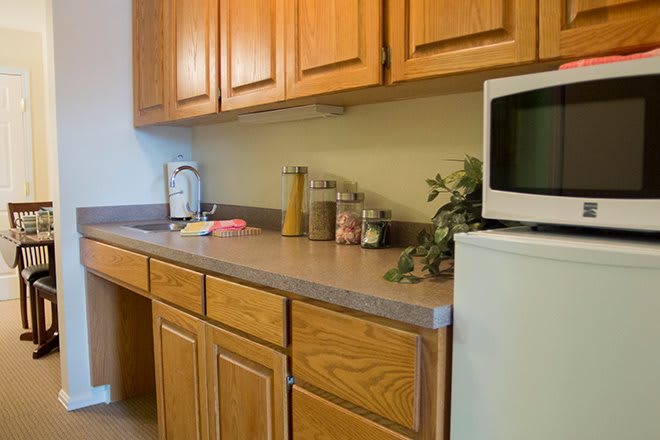 A kitchen countertop with wooden cabinets, a microwave, and a Keurig coffee maker.