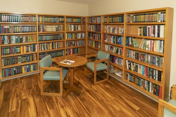 A cozy library corner with bookshelves, a round table, and chairs.