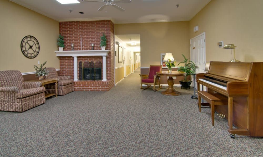 A cozy living room with a brick fireplace, carpeted floor, and comfortable seating.