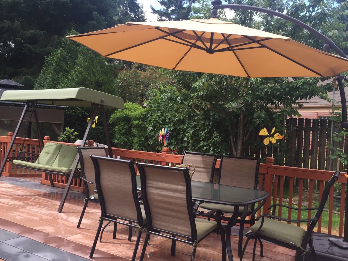 A cozy outdoor patio with a table and chairs under a large umbrella.