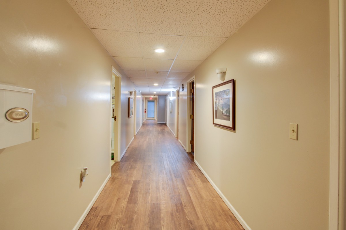 A well-lit hallway with wooden flooring and artwork adorning the walls.
