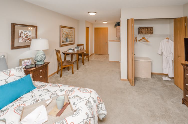 A cozy bedroom interior with a comfortable bed, small dining table, and open closet.