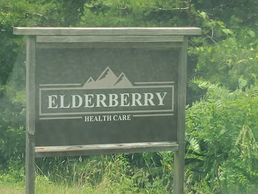 Sign for Elderberry Health Care surrounded by greenery.