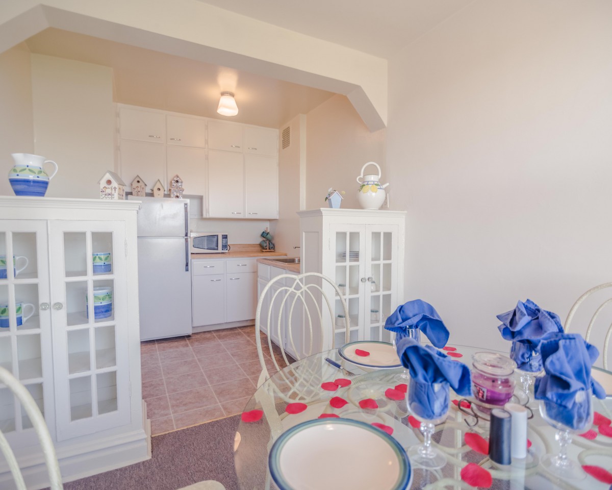 A cozy dining area with a view into the kitchen, featuring a beautifully set table with blue napkins.