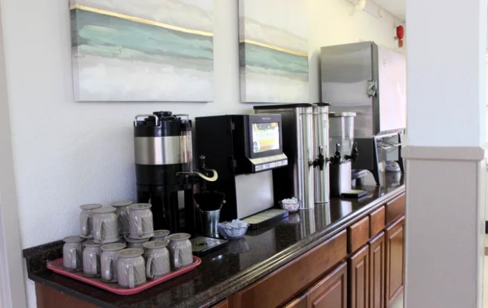 A self-serve coffee and beverage station with various machines and cups arranged on a counter.