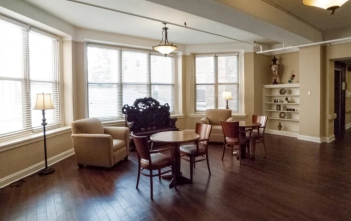 A cozy, well-lit living area with comfortable seating and library shelves.