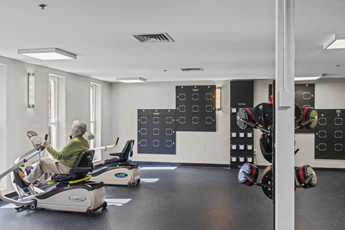 A modern gym with exercise equipment and ample natural light.