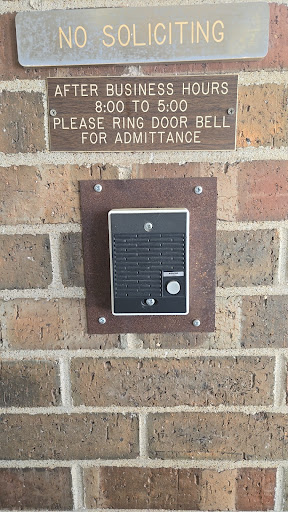 A doorbell mounted on a brick wall with a sign requesting visitors to ring it for entry.