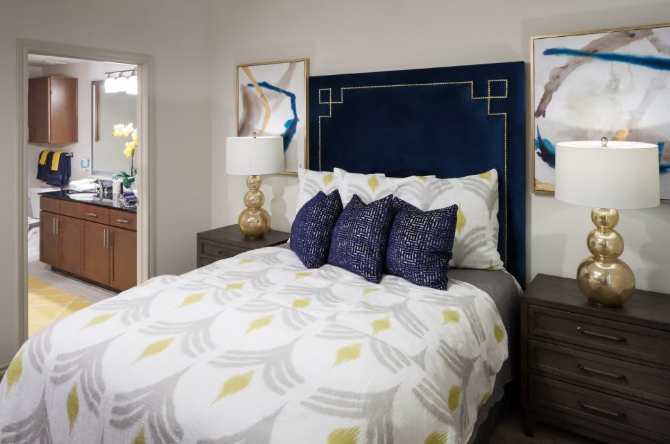 A stylish bedroom with a modern design featuring a blue headboard, decorative pillows, and contemporary artwork.
