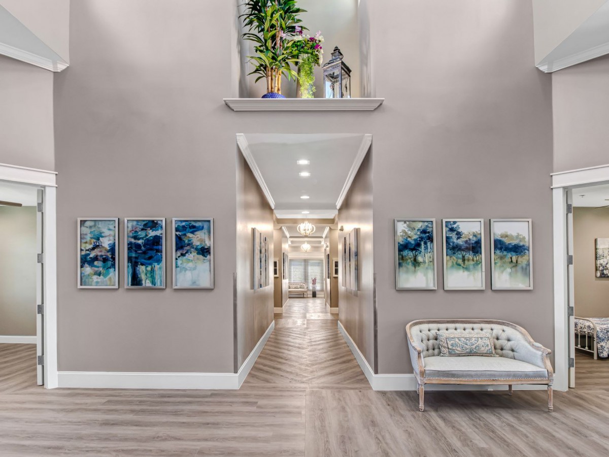 A modern hallway with elegant artwork and plants, featuring wood flooring and contemporary lighting.