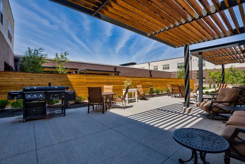 A modern outdoor patio with seating and a pergola under a clear blue sky.