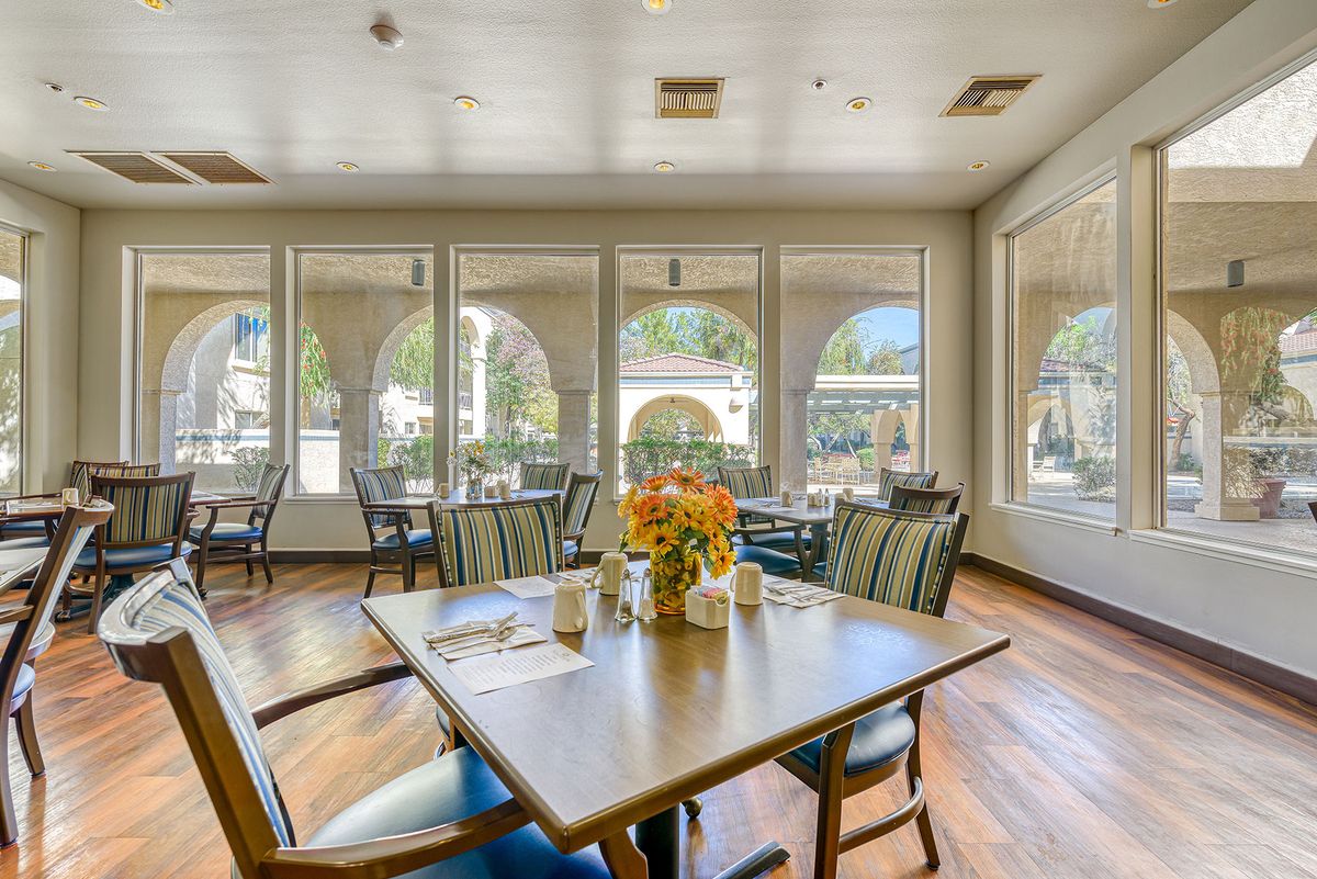A bright and spacious dining room with large windows, tables, and chairs.