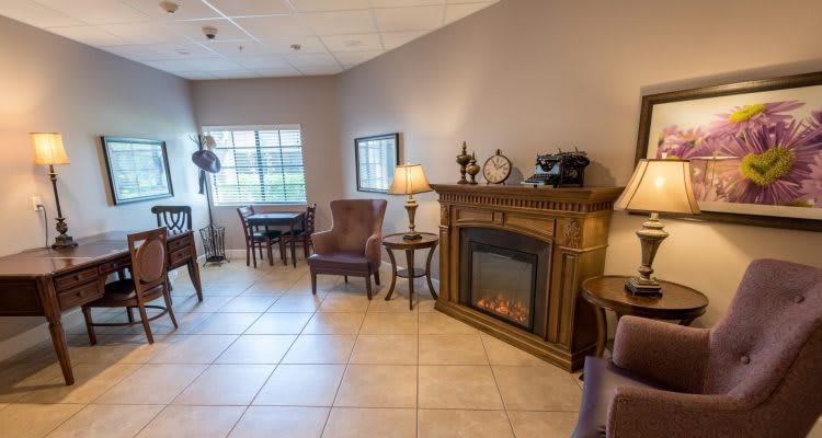 A cozy living room featuring a decorative fireplace, comfortable seating, and classic furnishings.