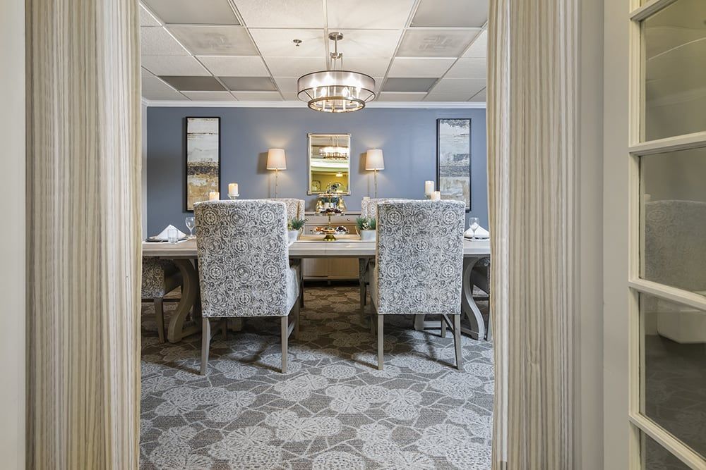 A sophisticated dining room with a formal setting, featuring elegant chairs and a chandelier.