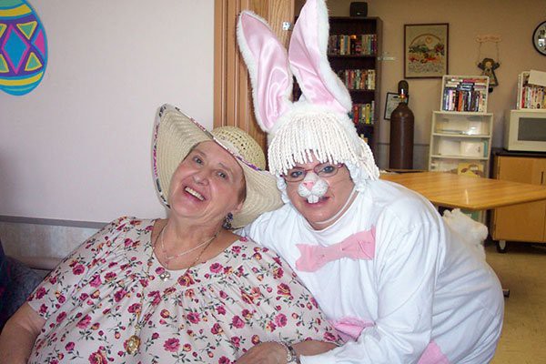 Two people enjoying a cheerful moment, one dressed in an Easter bunny costume.