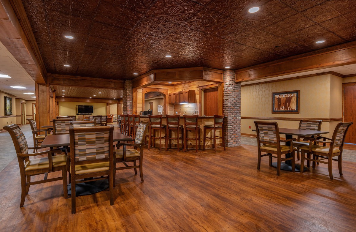 A cozy restaurant interior with a bar and seating area, featuring warm lighting and wooden floors.