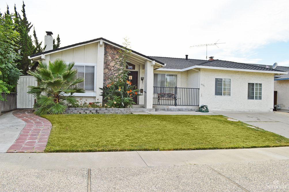 A single-story suburban house with a well-maintained lawn and a driveway.