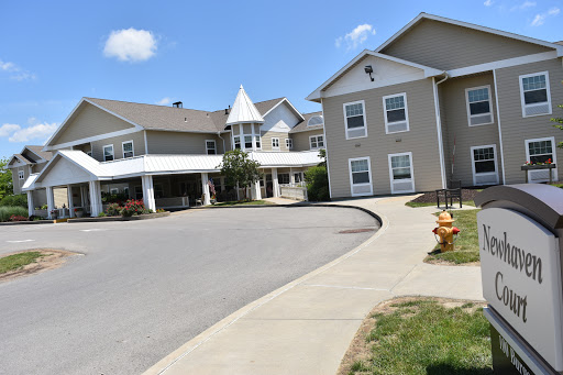 A view of a multi-story residential building with a curved driveway under a clear blue sky.