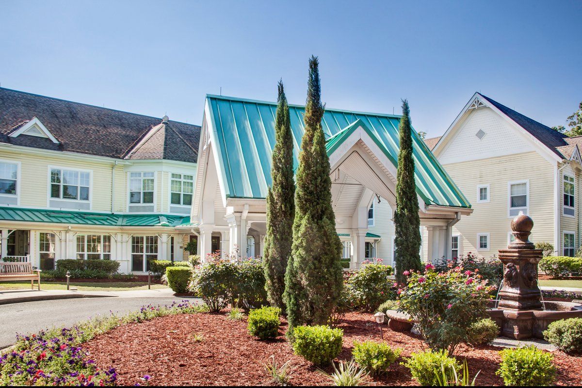 A charming building with a green roof and manicured landscaping on a sunny day.