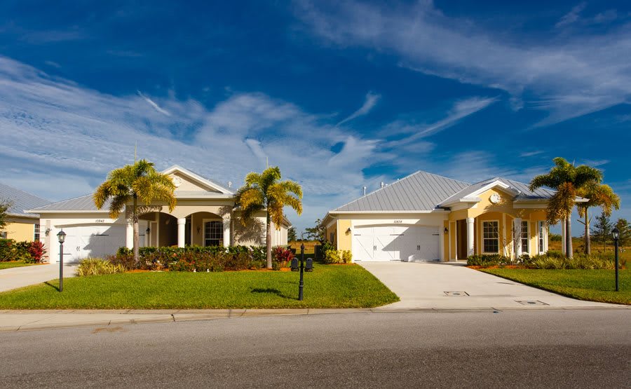 A picturesque suburban neighborhood featuring two houses with palm trees in the front yard.