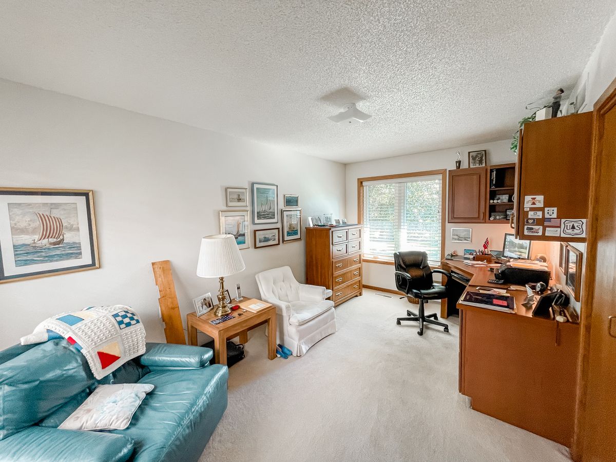 A cozy living room with a home office setup, featuring comfortable seating and decorative elements.