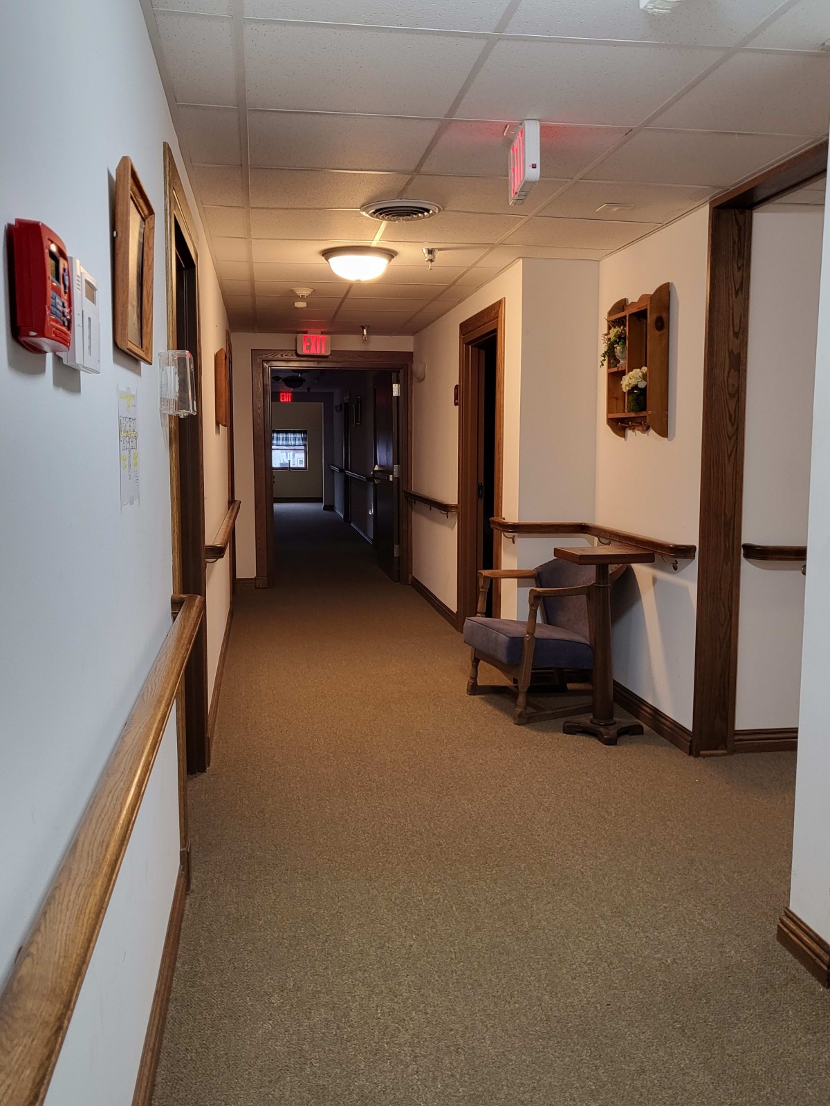 A well-lit hallway with a chair and framed pictures on the walls.